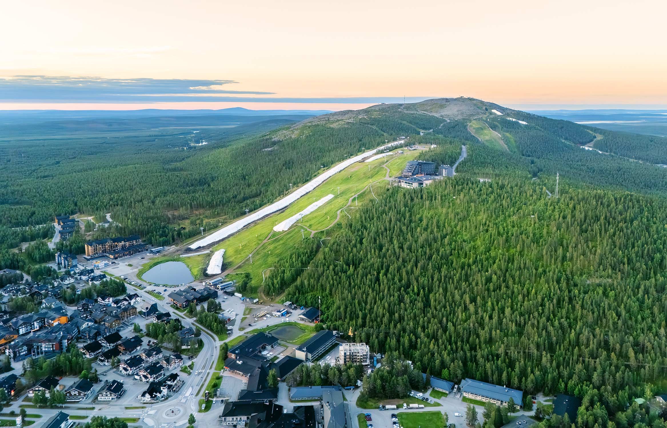 An aerial view of a town with a ski resort, including buildings, roads, and a ski lift.
