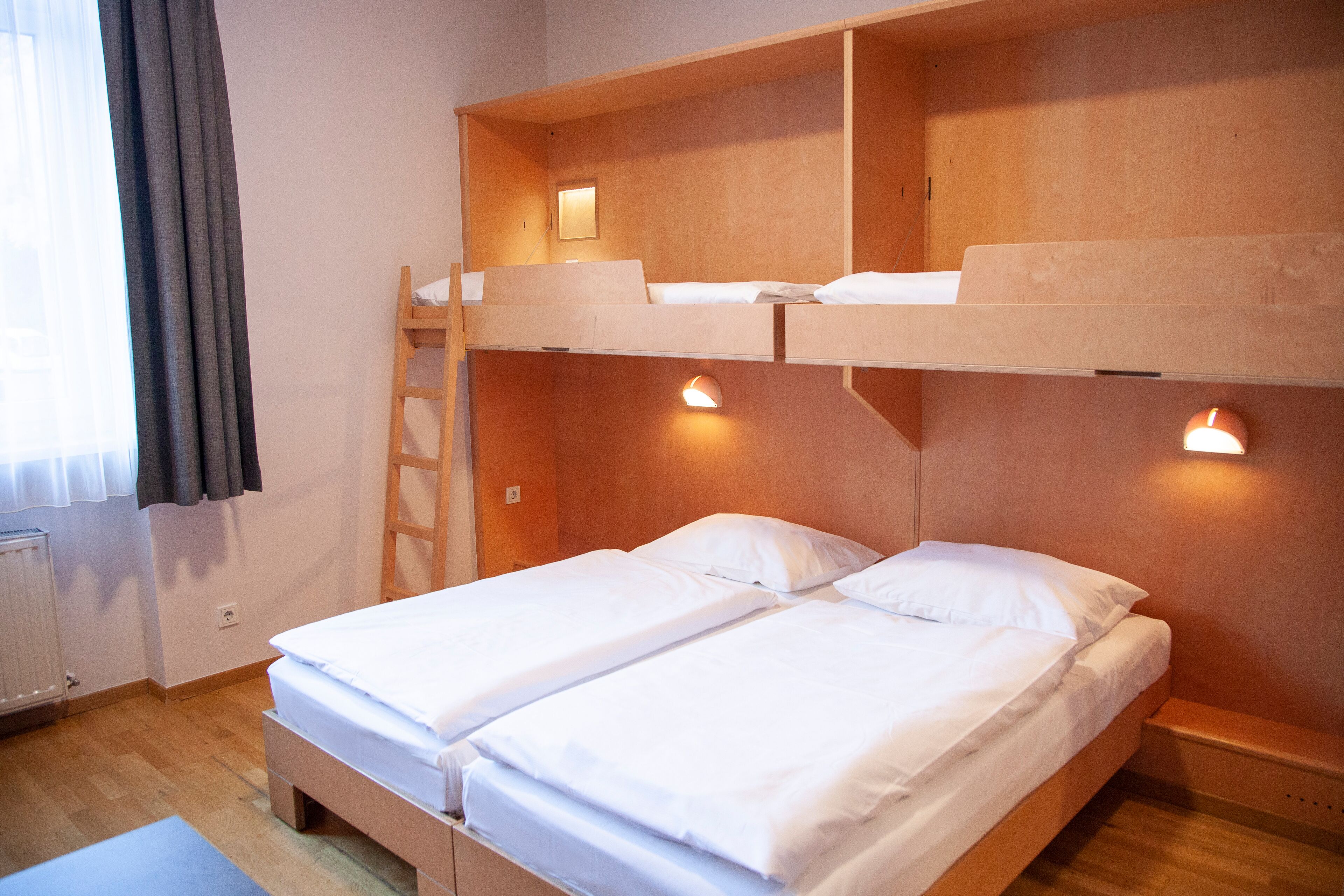 A bunk bed room with two beds, a ladder, and wall-mounted lights.