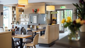 Um restaurante moderno com área de bar, lugares para sentar e cozinha visível ao fundo.