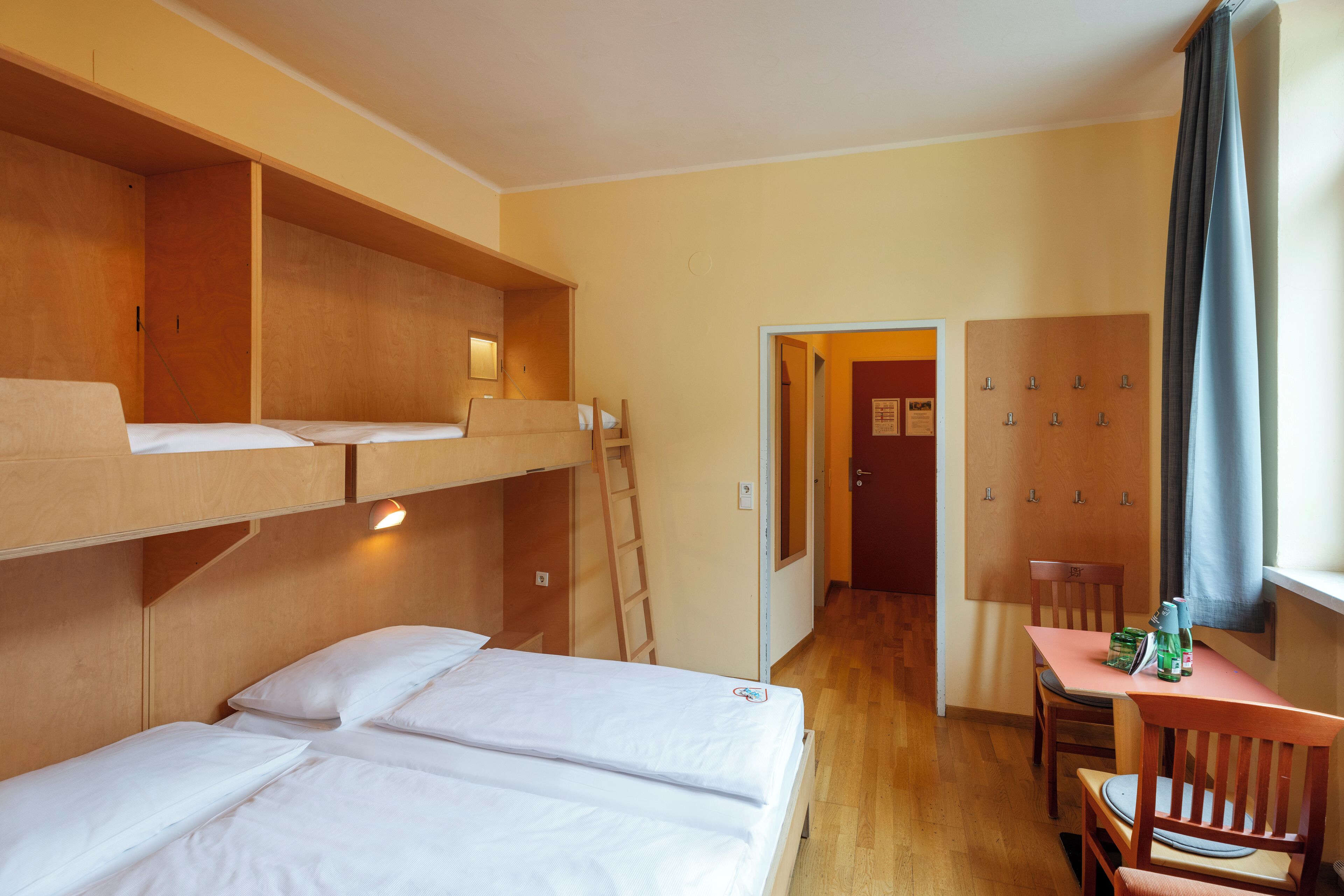 Una habitación con literas, un escritorio y una silla.