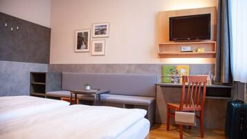 A hotel room with a bed, a sofa, a TV, and a desk.