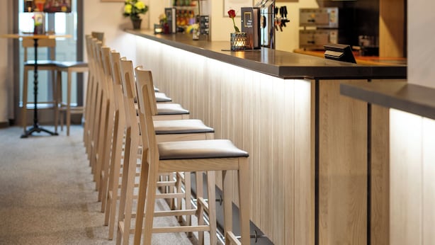 Uma área de bar moderna com cadeiras de madeira e luminárias pendentes pretas.