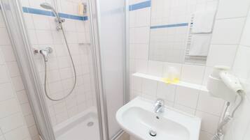 A bathroom with a glass-enclosed shower, a sink, a towel rack, and a hairdryer.