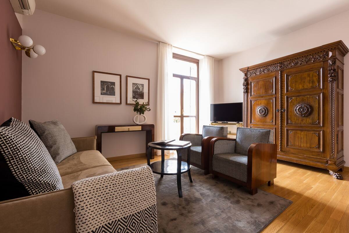 A living room with a sofa, armchairs, a coffee table, and a wooden cabinet.