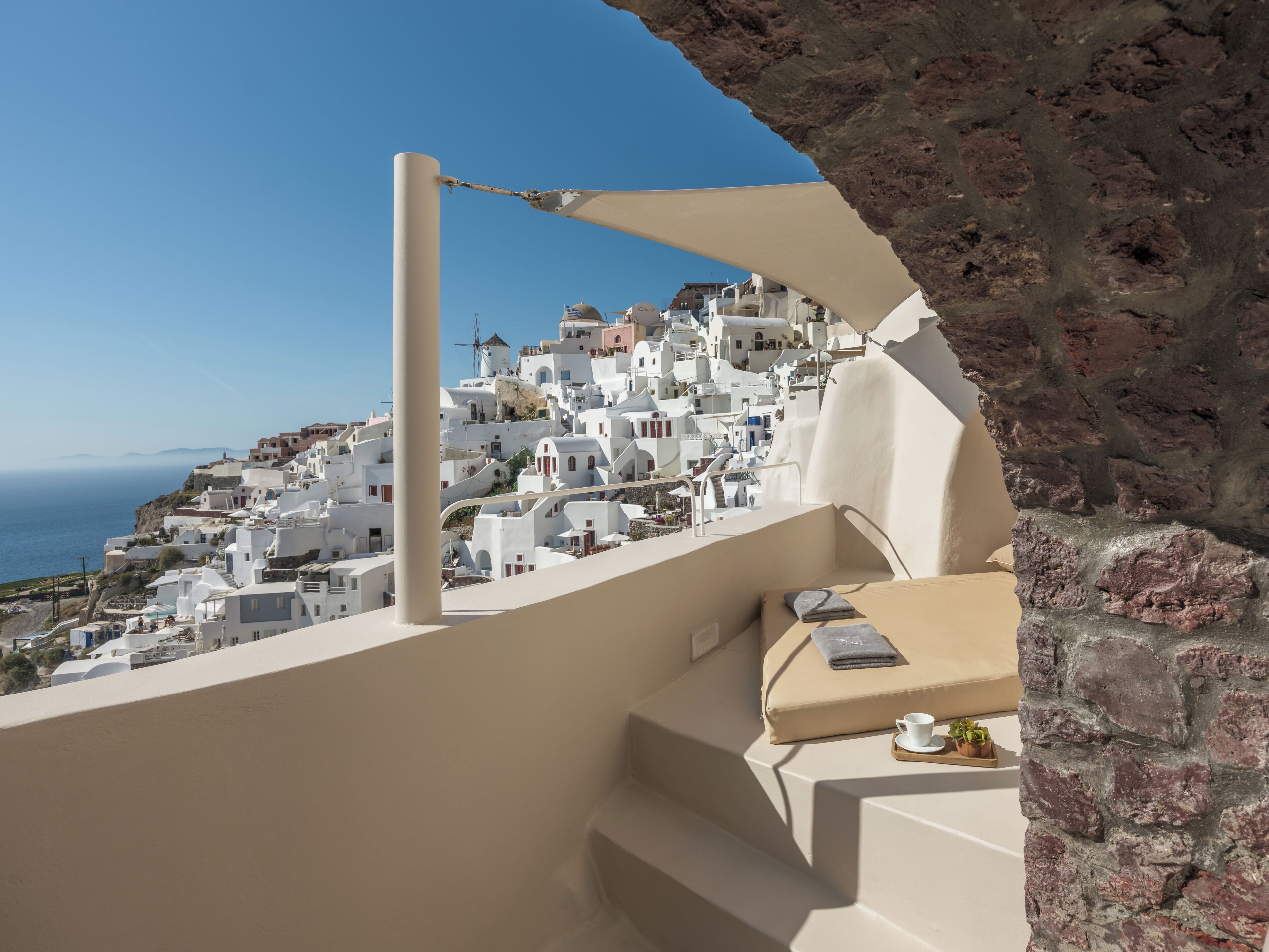 A view of white-washed buildings with a clear blue sky and the sea in the background.