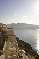 A coastal building with a view of the sea, featuring a staircase and a small outdoor seating area.