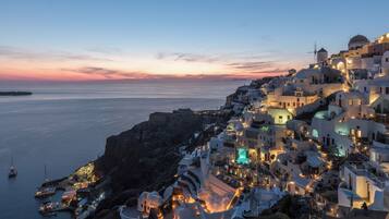 A coastal town with white buildings, a marina, and a sunset view.