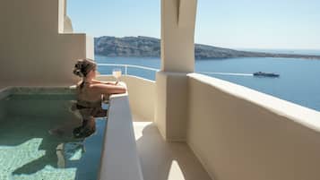 A person relaxing in a pool with a view of the sea and a boat.