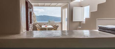 A room with a view of the sea, a dining area with a table and chairs, and a bathroom with a bathtub.