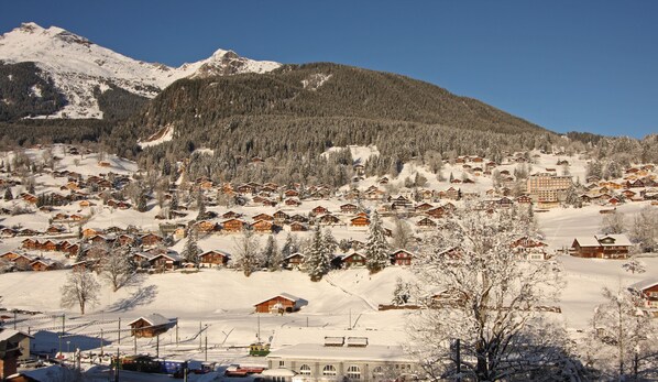 Un pueblo en la montaña cubierto de nieve, con cabañas de madera y una estación de esquí.
