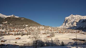 Pueblo en la montaña cubierto de nieve con casas de madera y una pista de esquí.