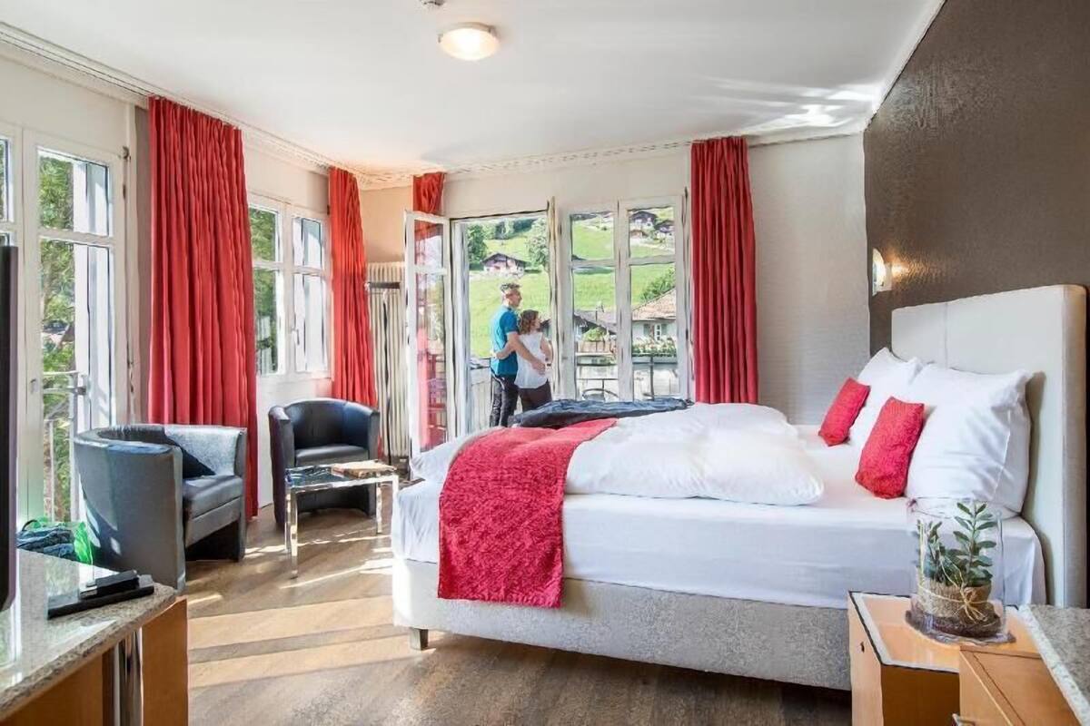 Quarto com cama, cadeira, escrivaninha e janela.