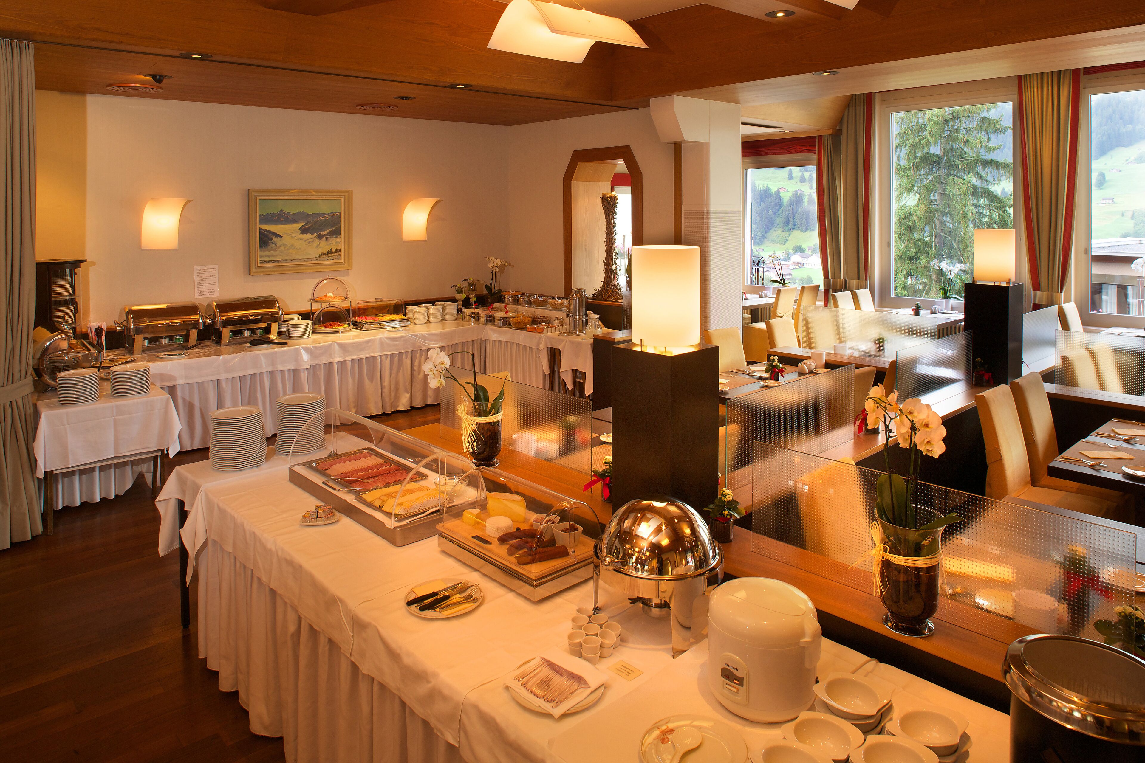 Een restaurantgedeelte in een hotel, met buffettafels, stoelen en tafels klaar voor het ontbijt.