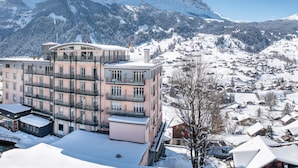A multi-story hotel with balconies overlooking a snowy mountain landscape.