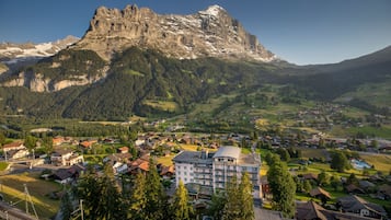 A mountain town with a prominent rocky peak, a central building with multiple floors, and surrounding residential houses.