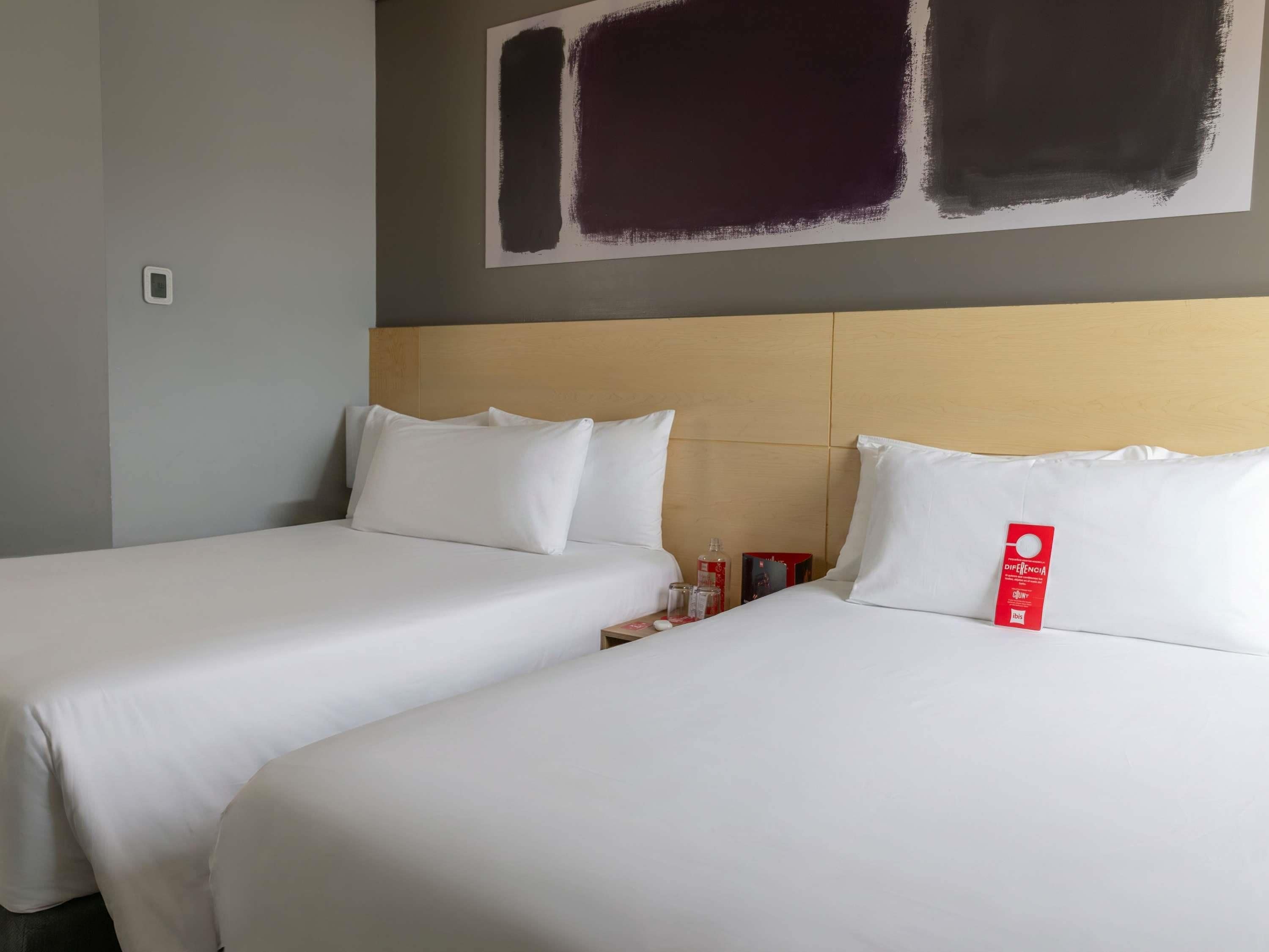 A hotel room with two beds, a wooden headboard, and a wall painting.