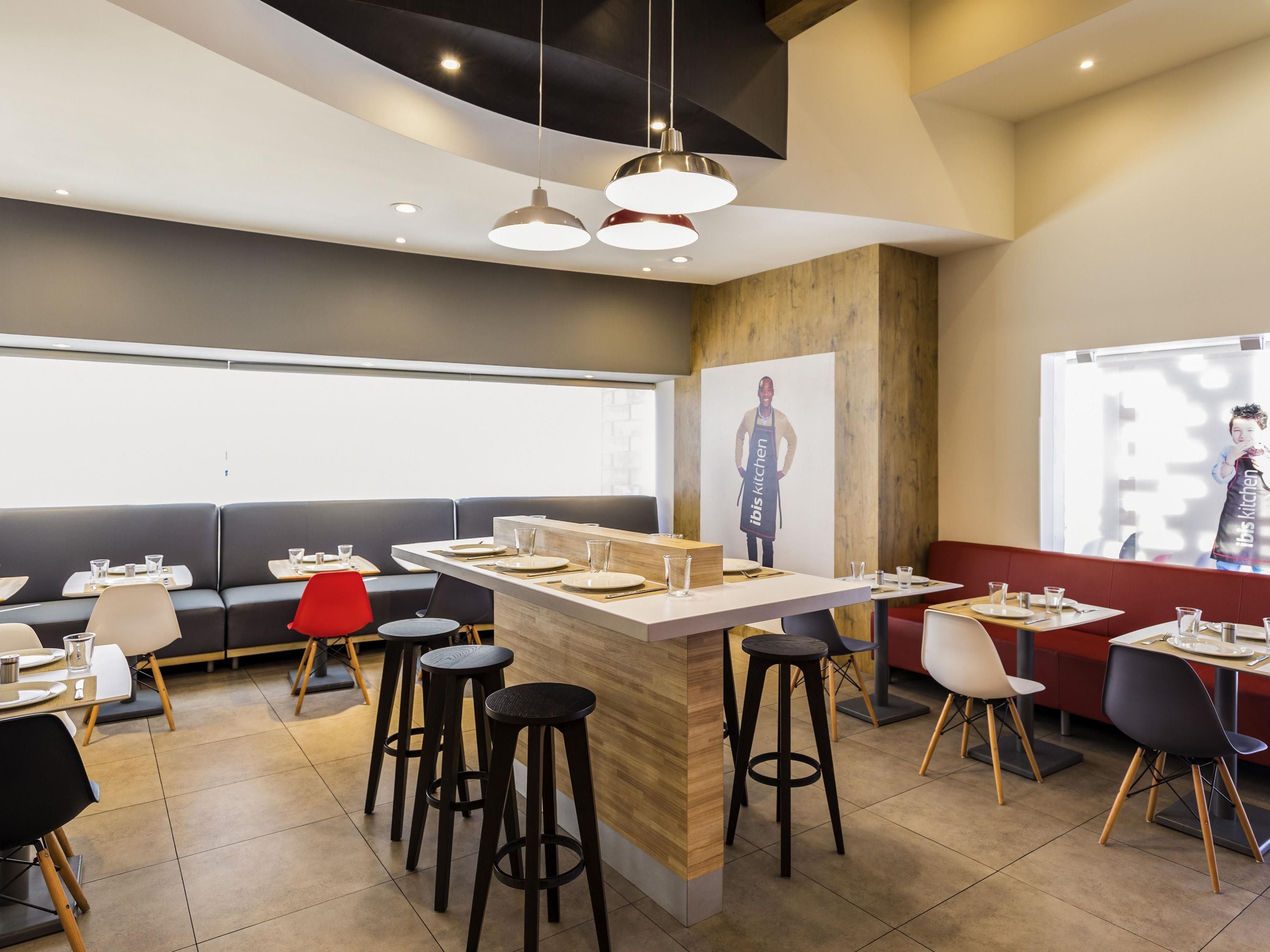 A modern restaurant interior with a central bar area, high stools, and booths.