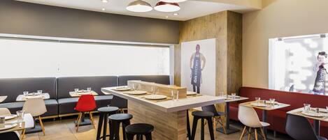 Un restaurante moderno con barra central, taburetes altos y cabinas.