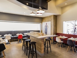 Un restaurante moderno con barra central, taburetes altos y cabinas.
