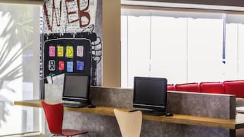 A modern workspace with two laptops on a wooden desk, two chairs, and a wall with a large 'WEB' sign.