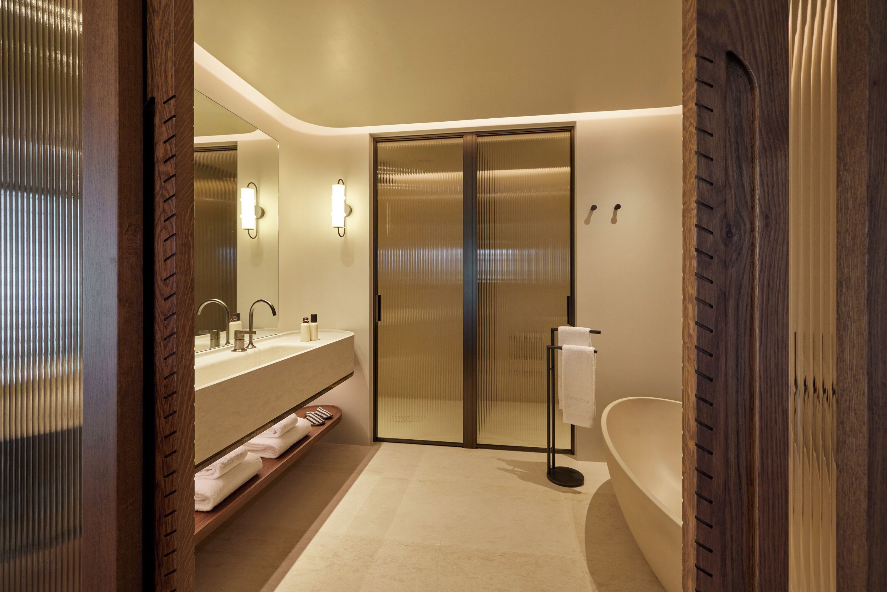 Un baño moderno con cabina de ducha de vidrio, bañera independiente y tocador con espejo y lavabo.