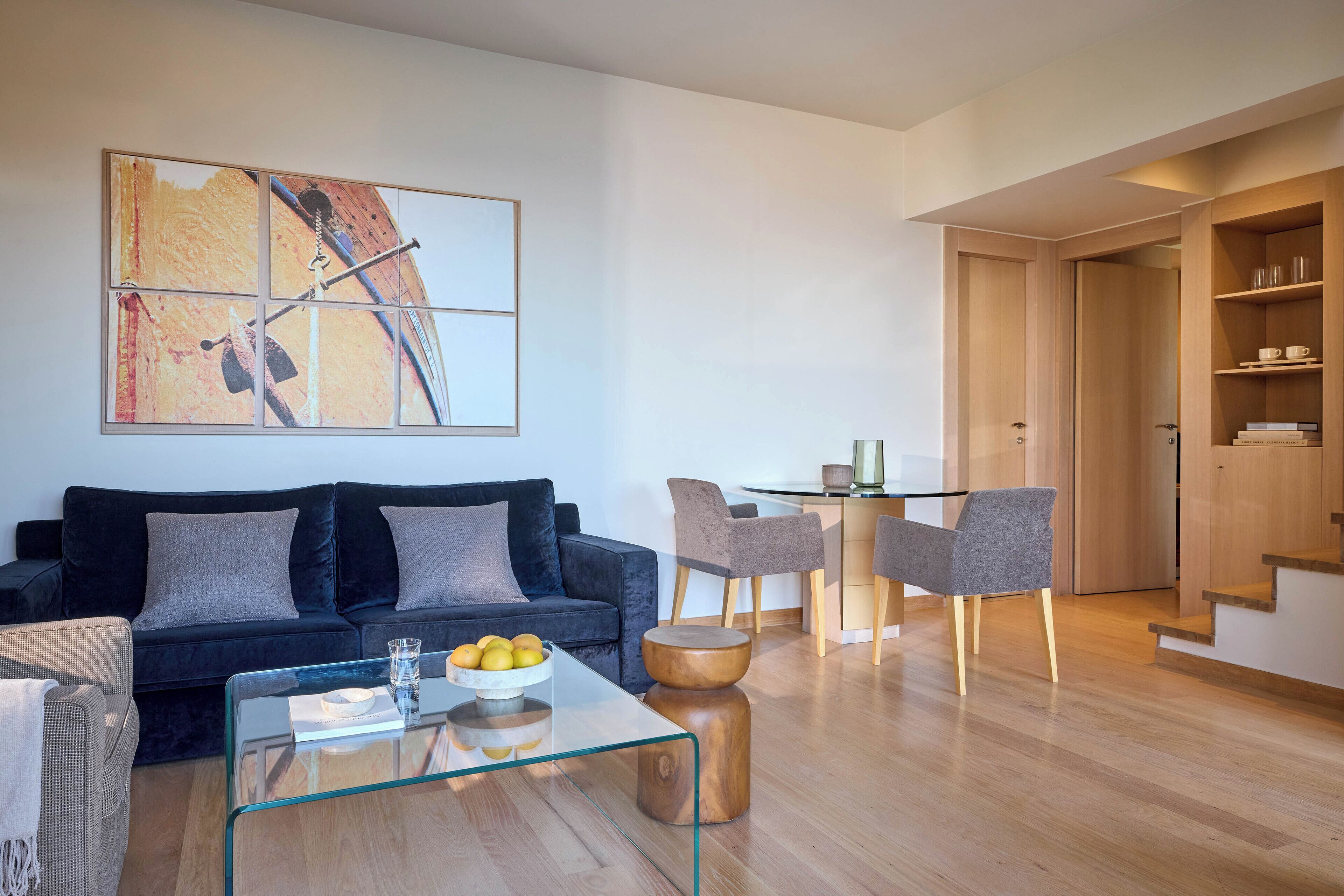 Un salon moderne avec un canapé bleu foncé, une table basse en verre et un coin repas comprenant une table et des chaises en verre.