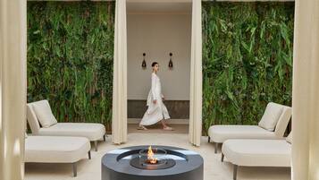 Un área de estar moderna con una chimenea central, dos sofás y una pared cubierta de vegetación.