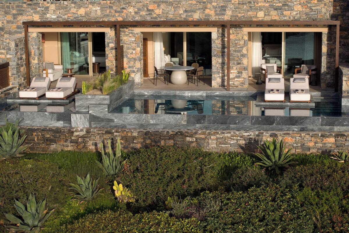 A modern house with a stone facade, outdoor seating, and a swimming pool.