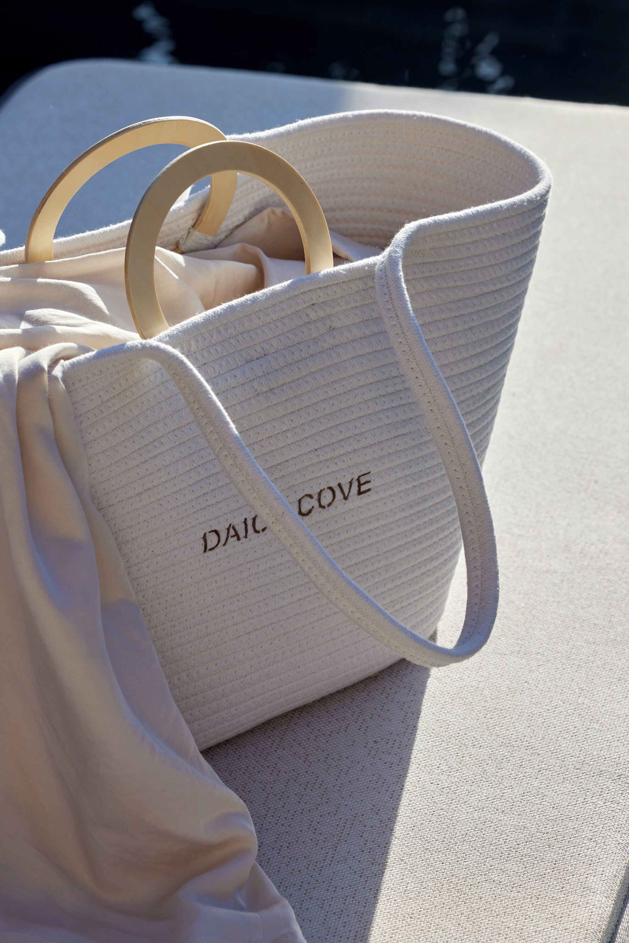 A white woven bag with the text "DAIC COVE" on it, placed on a textured surface.