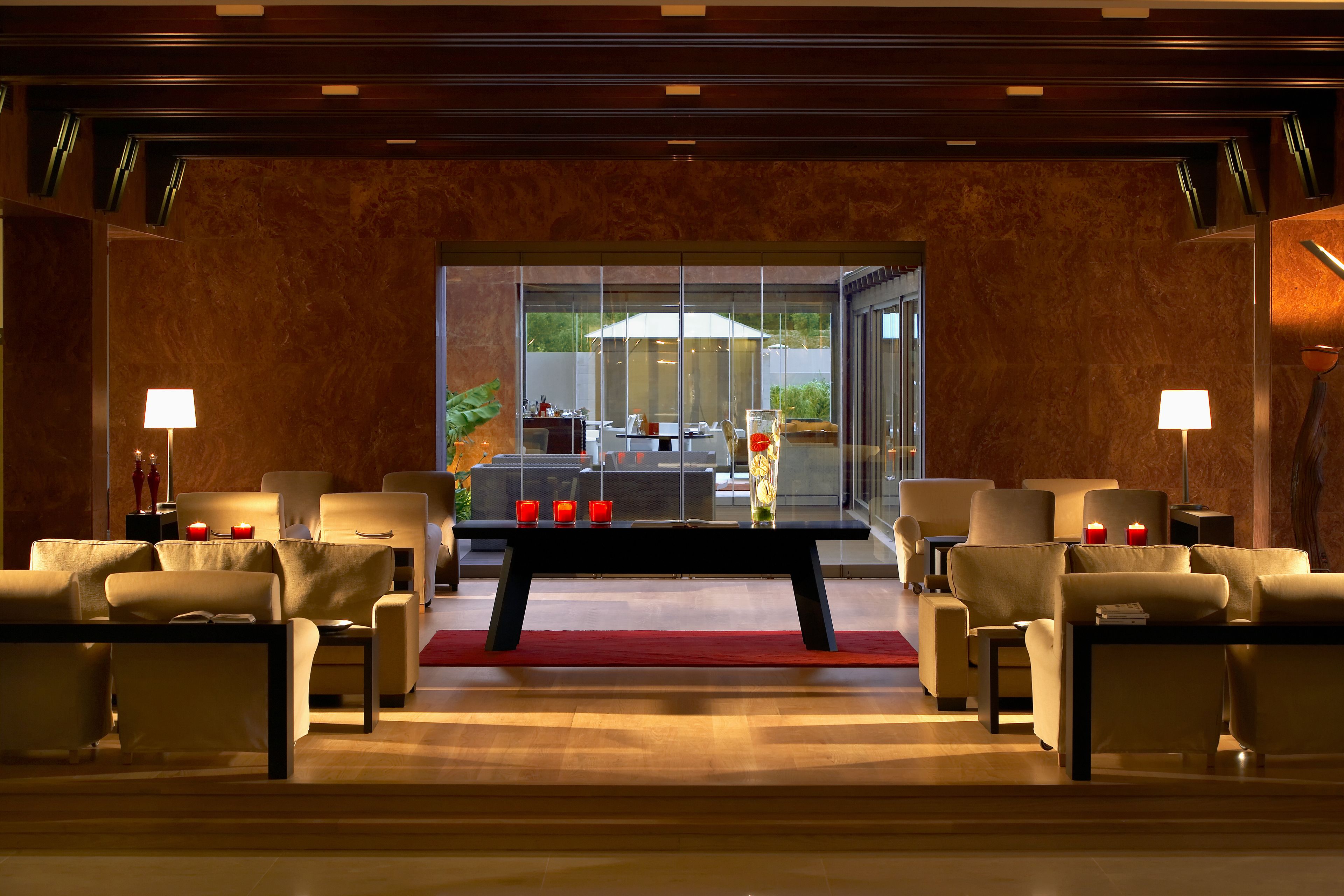 A modern lobby with leather sofas, a central coffee table, and a glass partition.