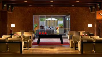Eine moderne Lobby mit Ledersofas, einem zentralen Couchtisch und einer Glastrennwand.