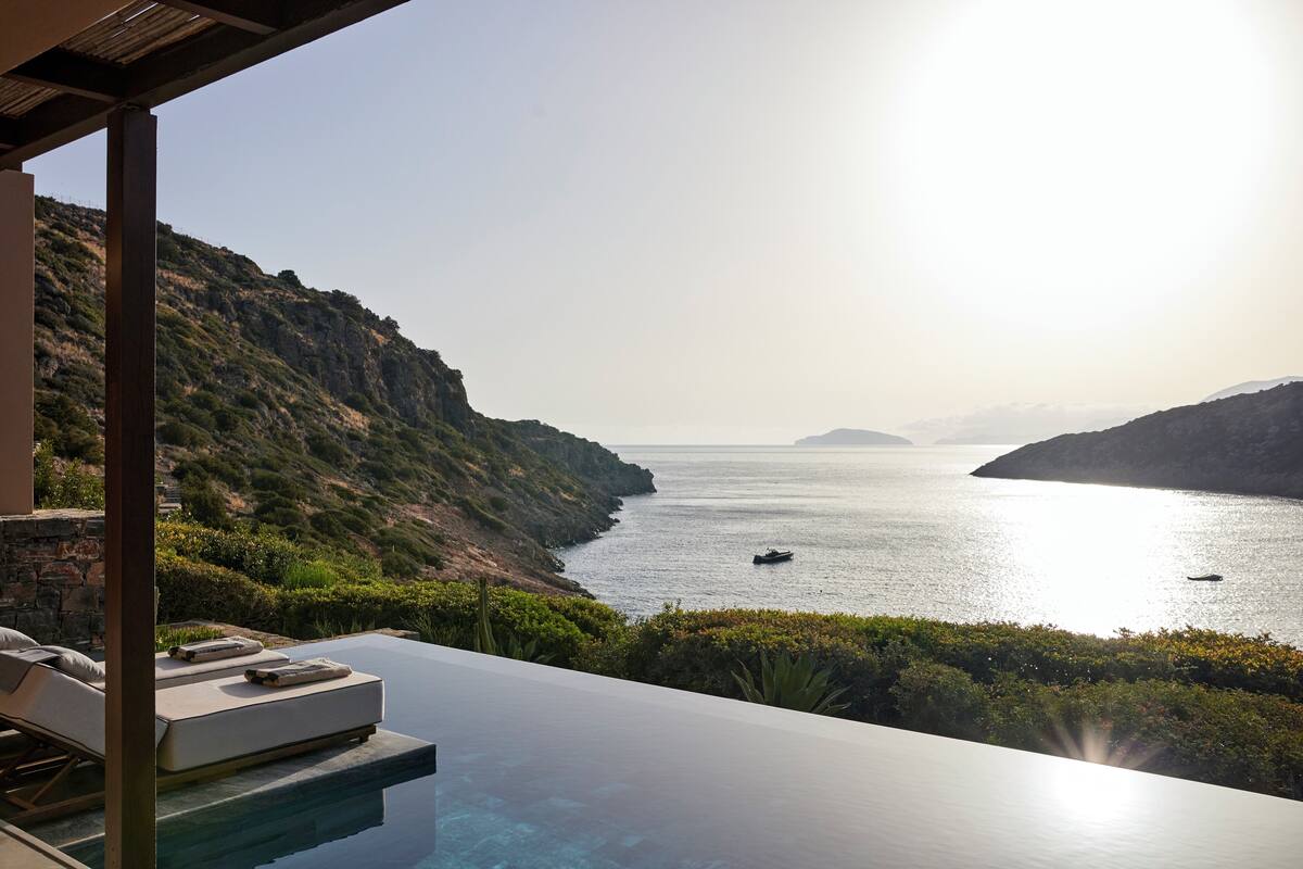 A poolside view overlooking a coastal landscape with a clear sky.