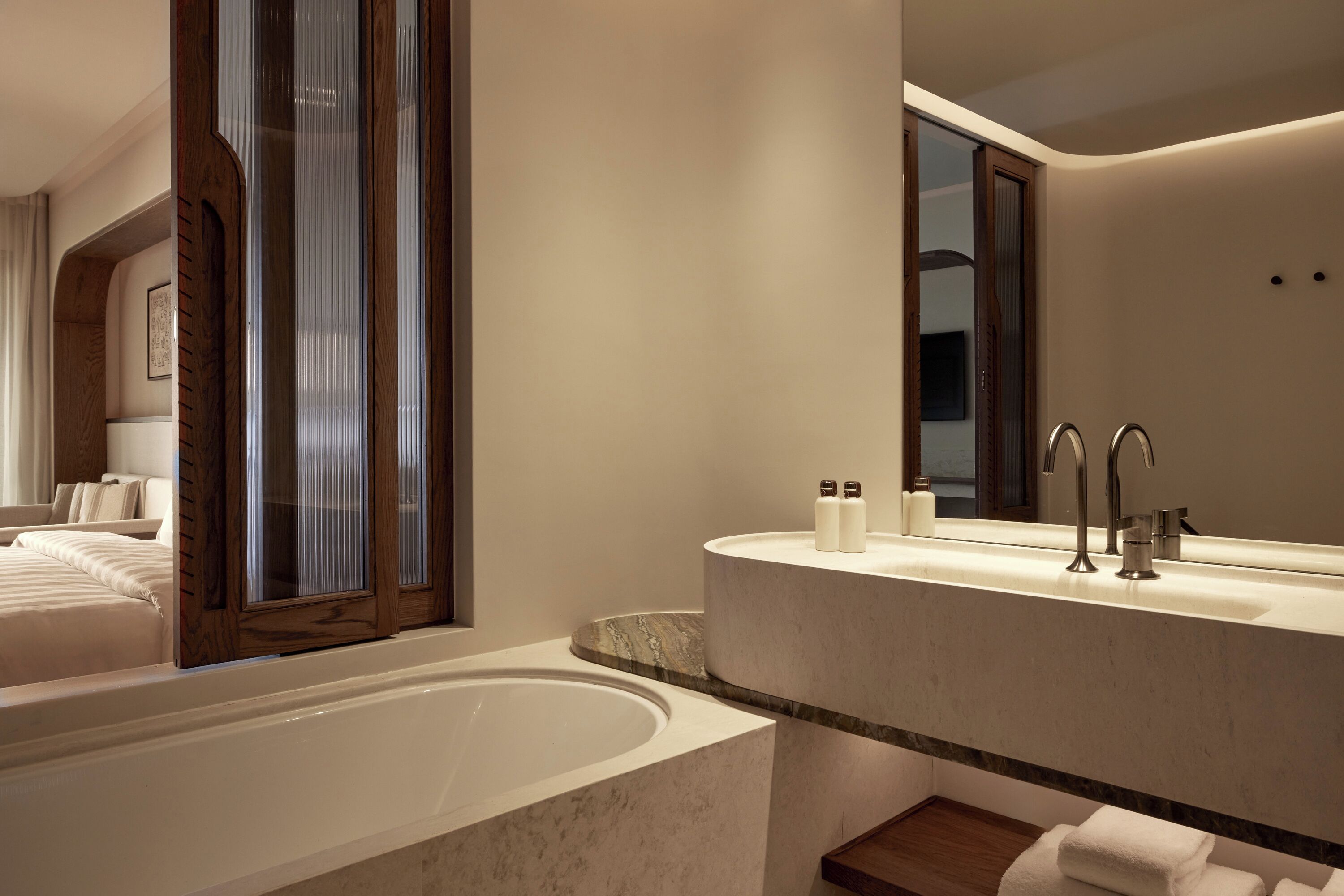 Un baño moderno con una bañera grande, un tocador con espejo y un estante de madera.