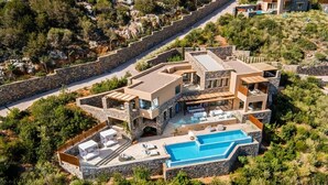 A modern multi-story house with a swimming pool, surrounded by lush greenery and stone walls. - Daios Cove (Agios Nikolaos)