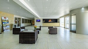 Een ruime lobby met een receptiebalie, een zithoek en een grote poster aan de muur.