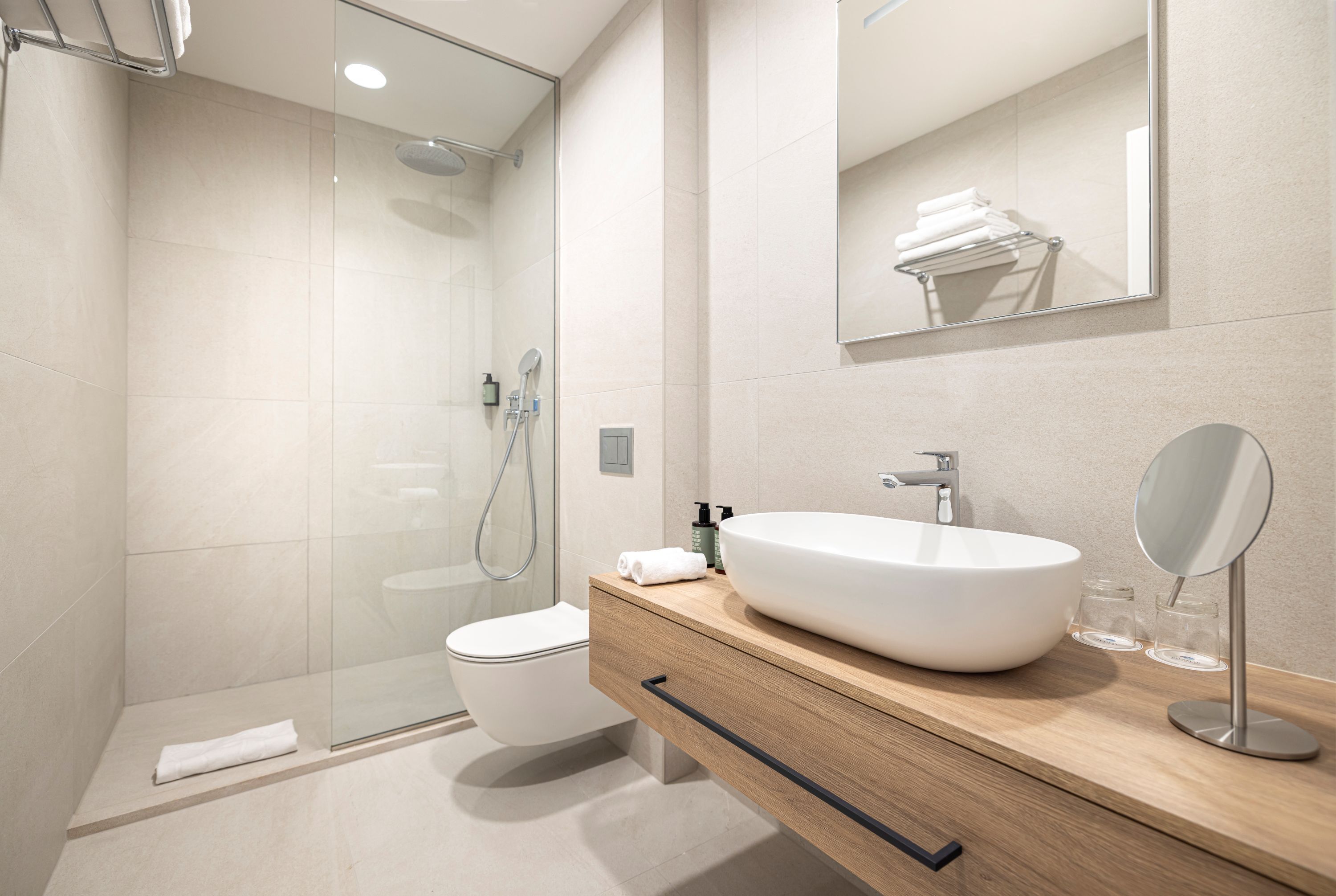 Ein modernes Badezimmer mit einer gläsernen Dusche, einem weißen Waschbecken und einer Holz-Kommode.