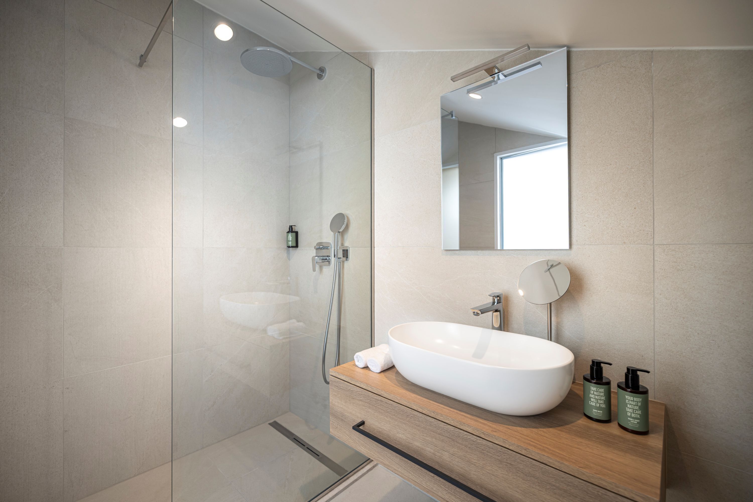 A modern bathroom with a large white sink, a mirror, and two bottles of shampoo.