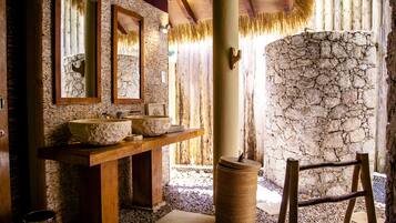 Un baño con pared de piedra, tocador de madera y un espejo grande.