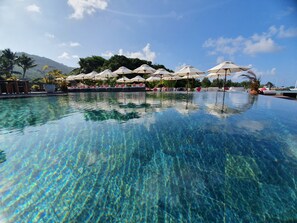Una piscina al aire libre, sombrillas, tumbonas
