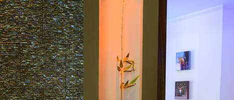 A room with a bed, a wall-mounted shelf with a vase, and a textured wall.