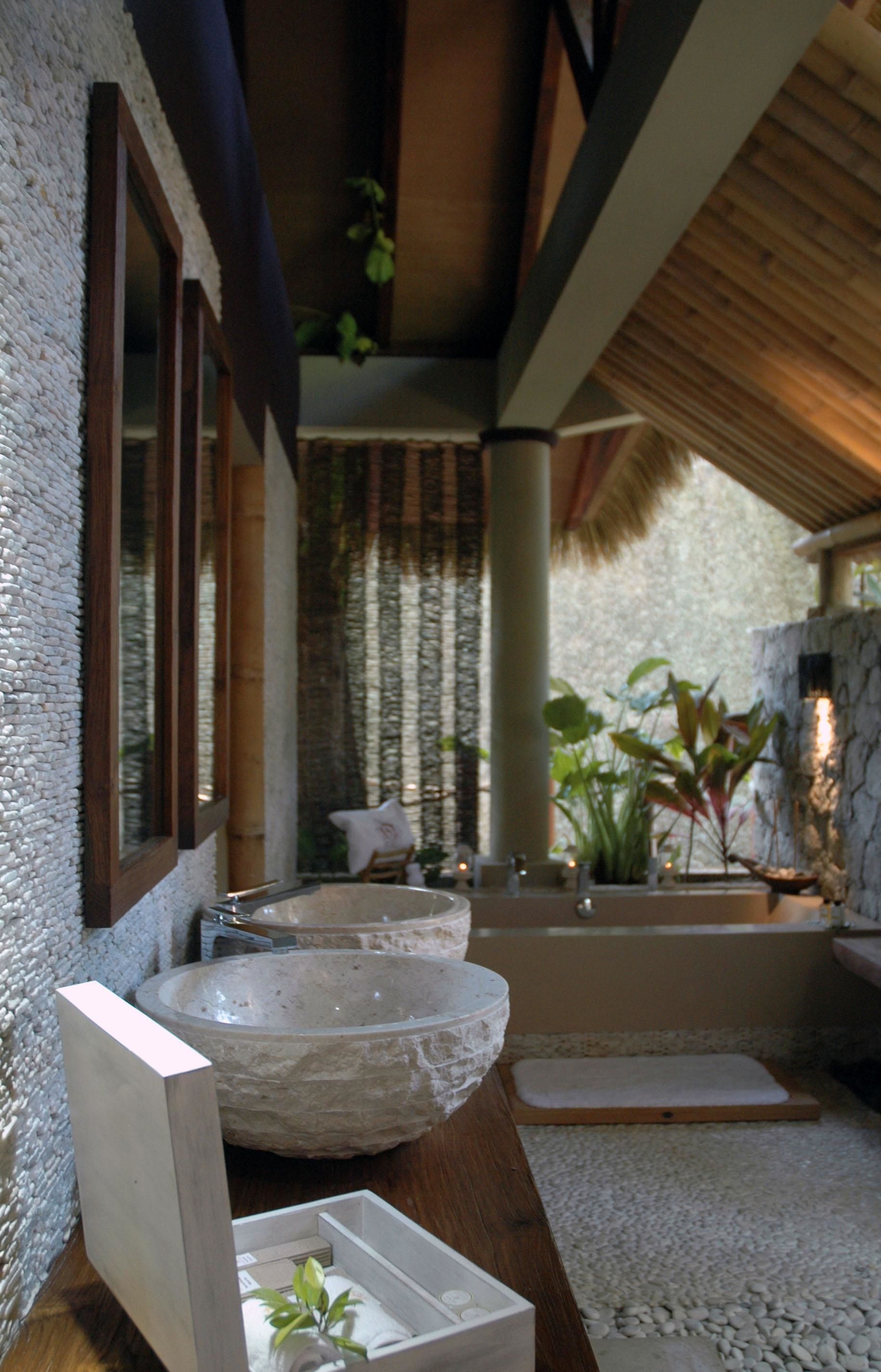 A bathroom with a large stone sink, a bathtub, and a wooden vanity.