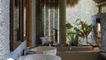 A bathroom with a large stone sink, a bathtub, and a wooden vanity.