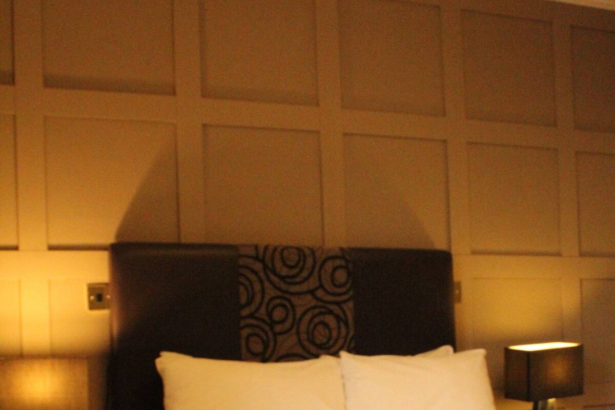 Een hotelkamer met een bed, nachtkastje en een behang met patroon.