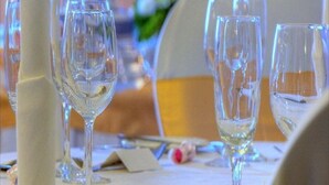 Une table dressée avec des verres à vin transparents, une serviette pliée et une petite carte, probablement pour un événement formel.