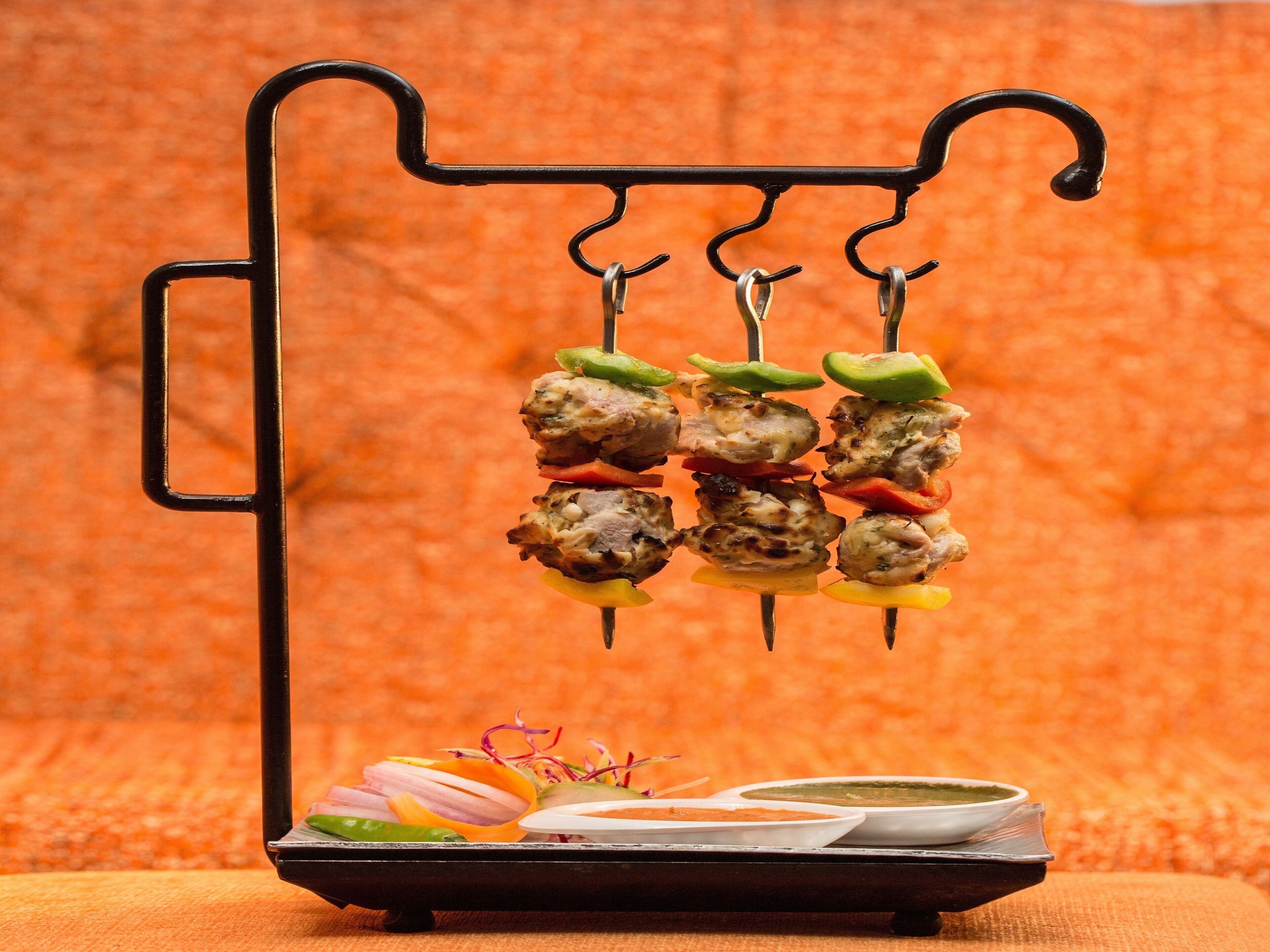 A meat skewer setup with vegetables and sauces.