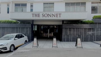 A building with a sign reading "THE SONNET" above the entrance. There are three "NO PARKING" signs in front.