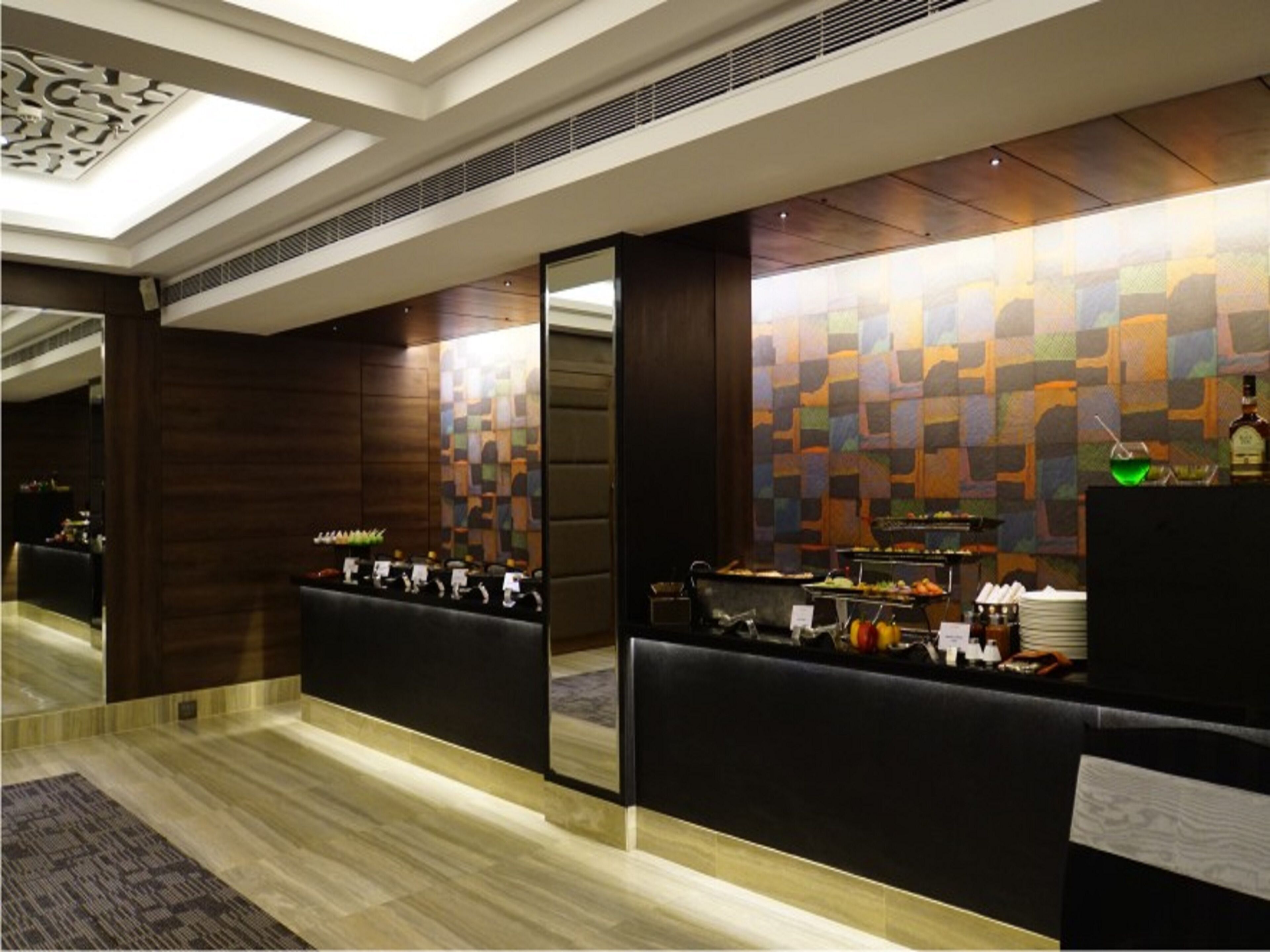 Un'area reception di un hotel dal design moderno, con una scrivania per il check-in, un angolo salotto e un muro decorato con un motivo geometrico.