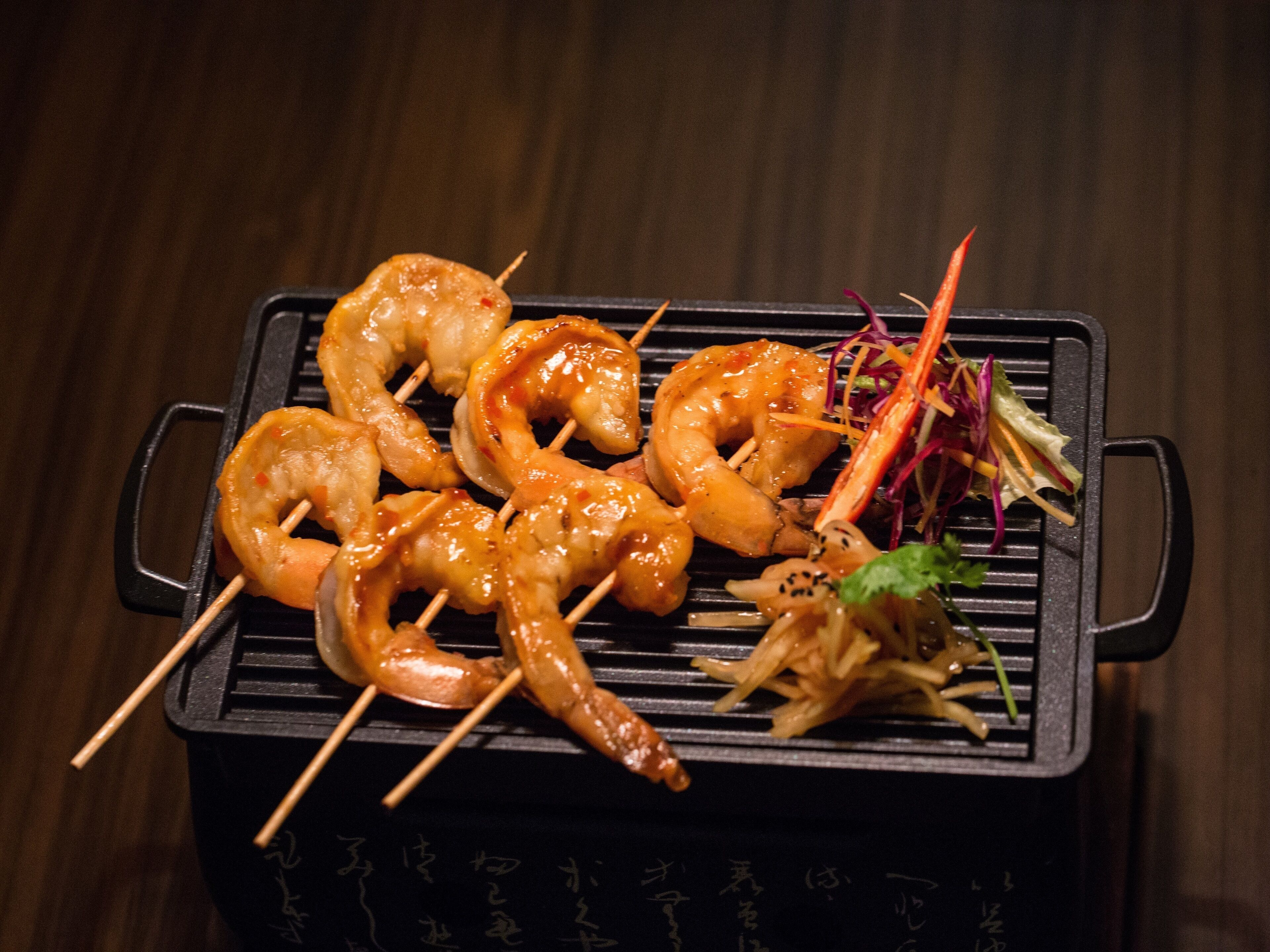 A grill with skewered shrimp and vegetables.