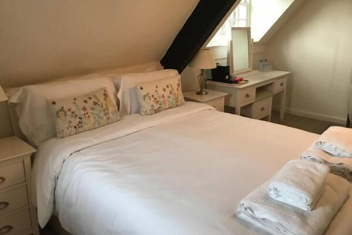 Ein Schlafzimmer mit einem Bett, einem Nachttisch, einer Kommode und einem Spiegel.