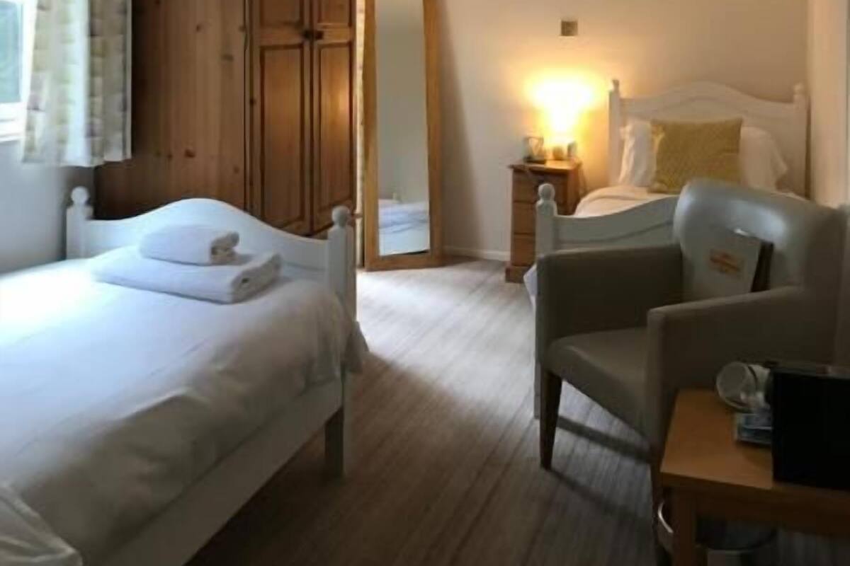 Ein Hotelzimmer mit einem großen Bett, einem Holzschrank, einem Schreibtisch mit Stuhl und einem Nachttisch mit Lampe.